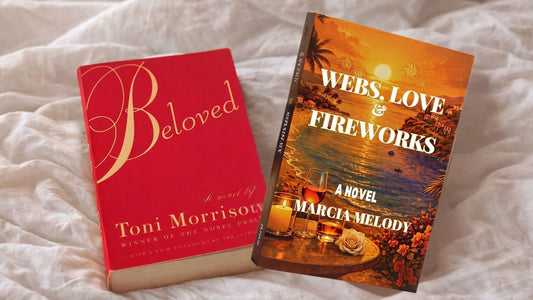Two paperback novels, Beloved by Toni Morrison and Webs, Love & Fireworks by Marcia Melody, resting side by side on white bedding in soft morning light.